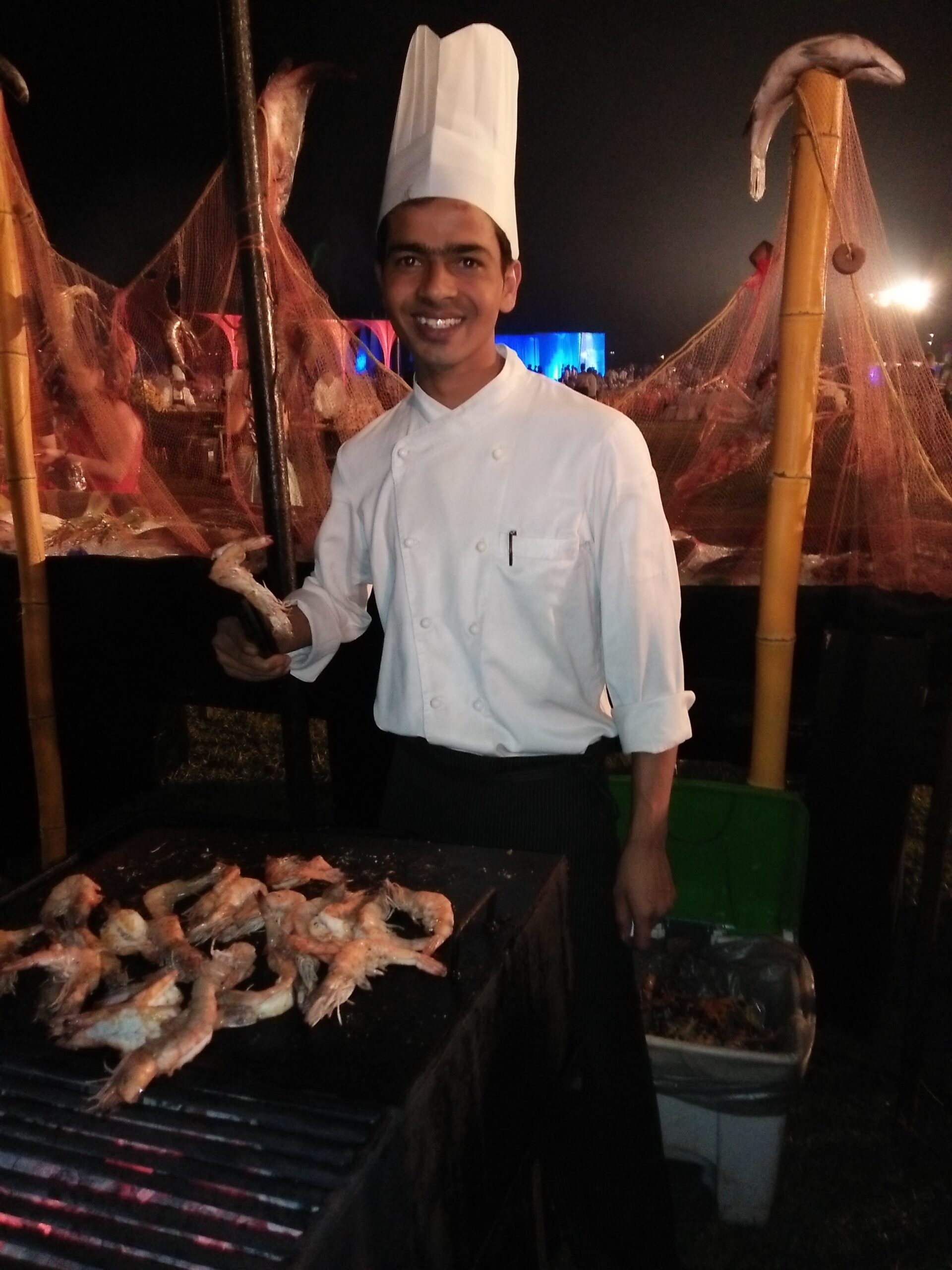 Street food chef grilling fresh prawns at a beachside stall in Goa at night