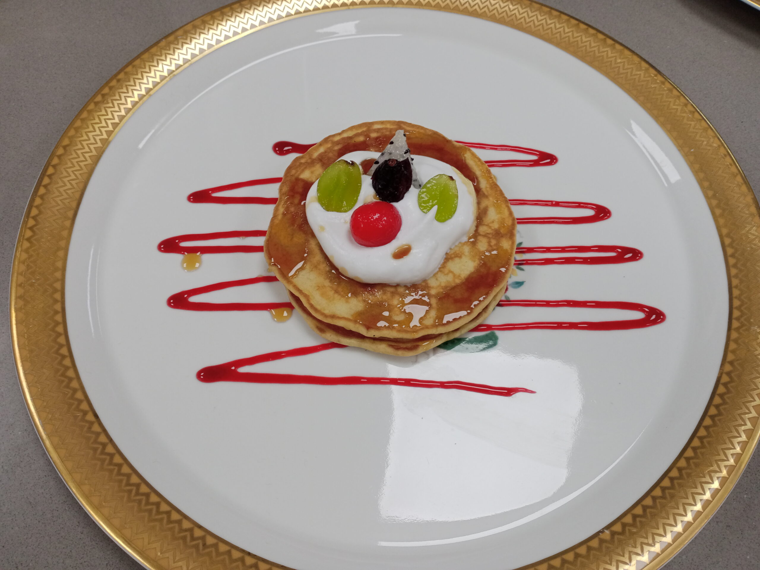 Fluffy stacked pancakes with whipped cream, fresh fruit and berry sauce