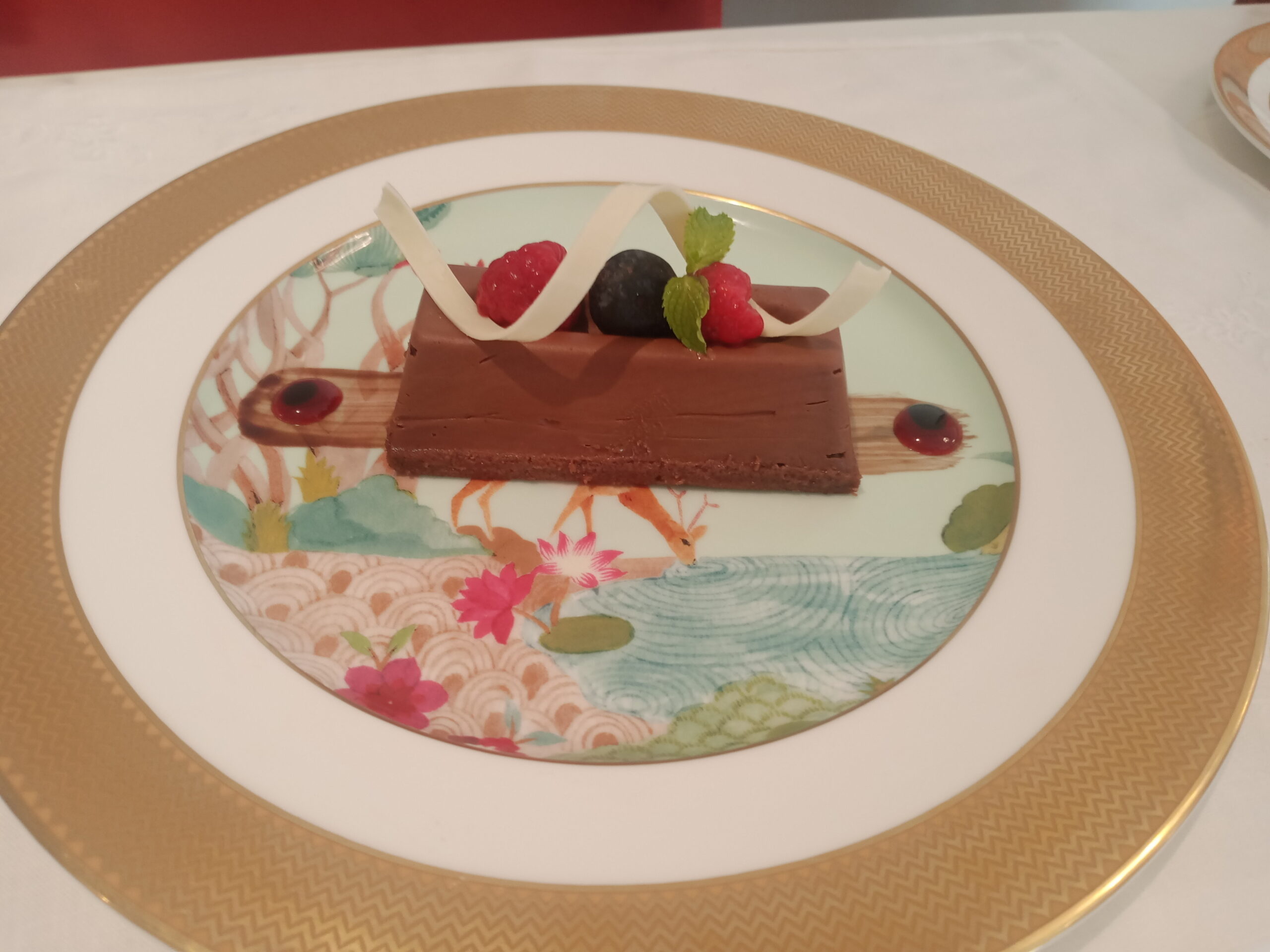 Elegant chocolate mousse bar with berries and mint on an ornate plate